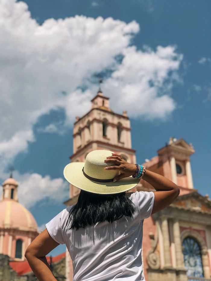 services-01 Back view of a tourist in a straw hat at the historic church in Tequisquiapan, Mexico.