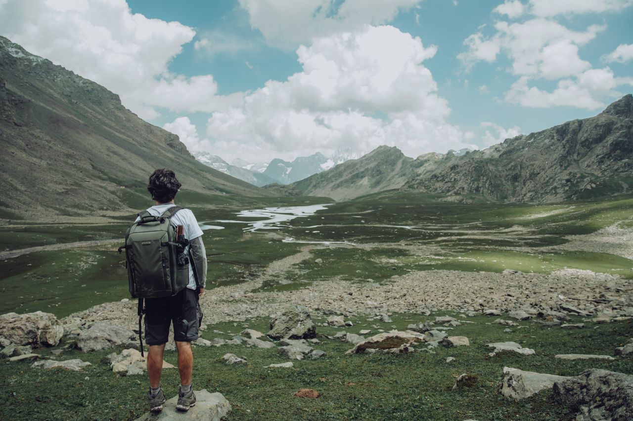 A lone hiker enjoys a stunning view in a vast mountainous landscape.